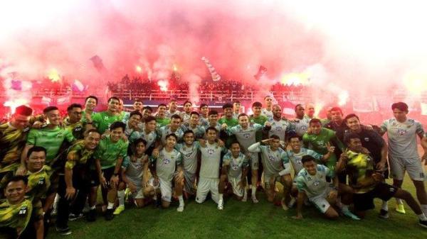 Pemain dan ofisial Persib Bandung berfoto dengan latar belakang bobotoh menyalakan flare di Stadion Sidolig, Bandung, Selasa (28/5/2024). Bobotoh memberikan dukungan kepada pemain yang akan menjalani laga kedua final Liga 1 2023-2024 di kandang Madura United, Jumat (31/5/2024).