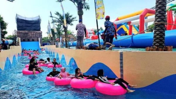 Pengunjung menikmati wahana Maui Wave Rider di Hawai Waterpark Malang, Minggu (16/6/2024).