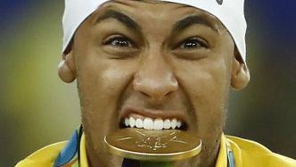 Brazil's Neymar bites his medal on the podium during the medal presentation following the Rio 2016 Olympic Games men's football gold medal match between Brazil and Germany at the Maracana stadium in Rio de Janeiro on August 20, 2016. <div class=