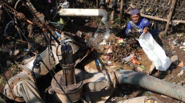 Petugas Polder Cipalasari 1, Nana Suntana (40) membersihkan sampah yang nyangkut dan menyumbat di pompa pengendali banjir Polder Cipalasari 1, Kampung Citeureup, Desa/Kecamatan Dayeuhkolot, Kabupaten Bandung, Jawa Barat, Kamis (12/9/2024).