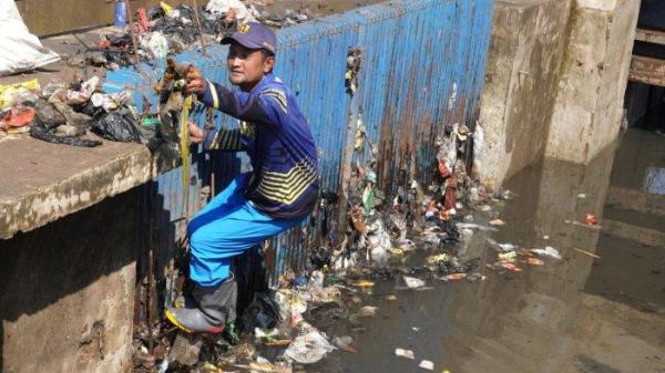 Petugas Polder Cipalasari 1, Nana Suntana (40) membersihkan sampah yang nyangkut dan menyumbat di besi penyaringan kolam penampungan air pengendali banjir Polder Cipalasari 1, Kampung Citeureup, Desa/Kecamatan Dayeuhkolot, Kabupaten Bandung, Jawa Barat, Kamis (12/9/2024).