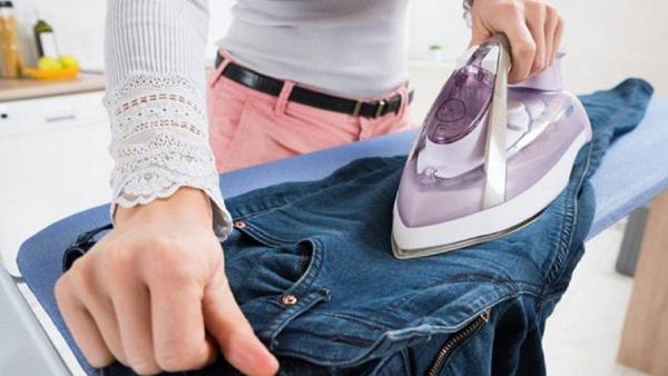 Ilustrasi menyetrika celana jeans menggunakan pelembut kain.