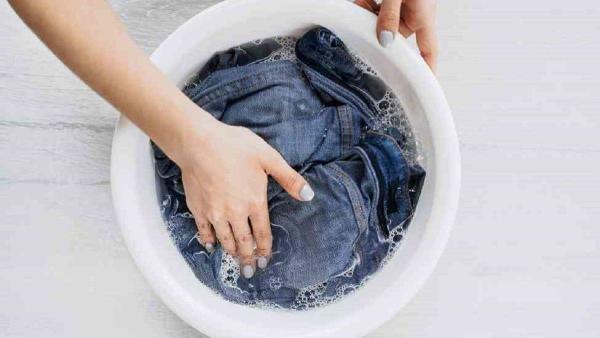 Ilustrasi merendam celana jeans dalam larutan cuka putih dan garam.
