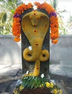 This may contain: an elephant statue with flowers around it