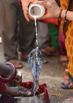 This may contain: a woman is pouring water from a faucet into her hands while others stand around