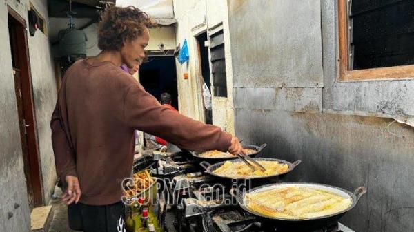 GORENG LUMPIA - Proses penggorengan lumpia di rumah Sukarsipah, Jalan Ngaglik, Gang Kuburan, Surabaya, Senin (3/2/2025). Usaha keluarga ini dimulai saat sang suami, Kasno berjualan sosis tempura di dekat Stadion Tambaksari, sekarang Stadion Gelora 10 November.