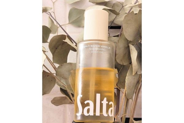 A bottle of body oil in front of leaves
