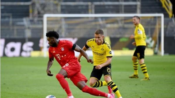 Gelandang Bayern Munich asal Kanada, Alphonso Davies (kiri) dan pemain depan Dortmund dari Belgia, Thorgan Hazard, berlomba merebut bola selama pertandingan sepakbola divisi satu Jerman (FEDERICO GAMBARINI / POOL / AFP)