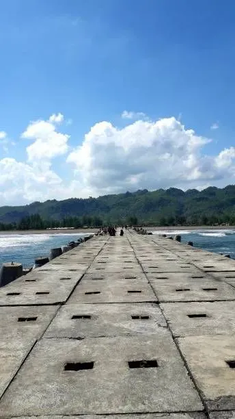 Beautiful background of Jetis Beach Cilacap Central Java with green hill and blue sky for wallpaper