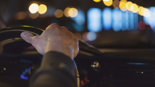 Close up of man hand on car steering wheel driving through a tunnel