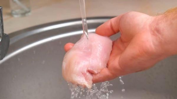 This may include: A person is washing it in a sink holding a piece of meat in his hand