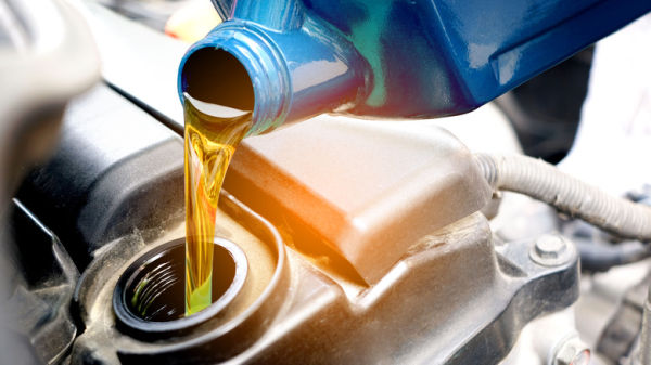 Pouring oil in engine from a blue bottle