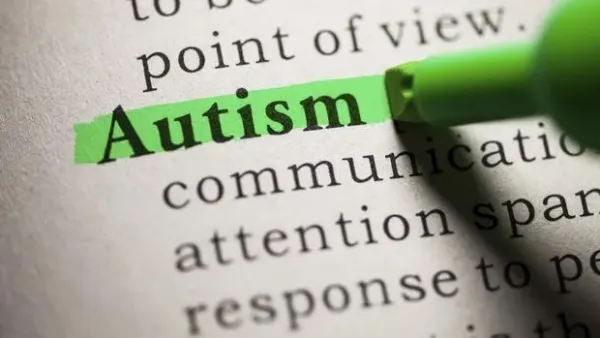 Word Autism built of wooden puzzles on a wooden background.
