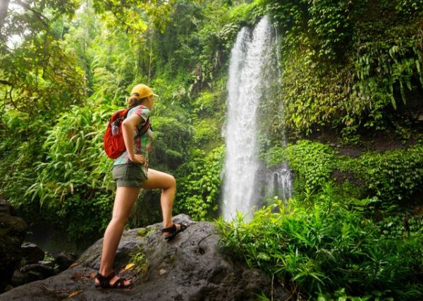 Ilustrasi wanita yang sedang hiking sambil menatap indahnya air terjun. Foto: soft_light/Shutterstock
