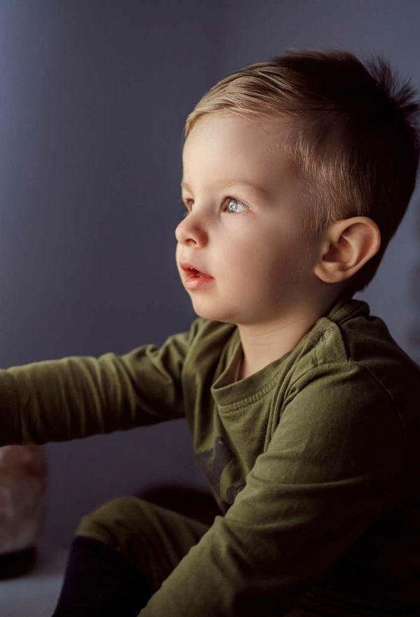   A child sits too close to the television ruining his eyes.