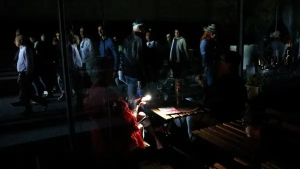 Tennis - Madrid Open - Park Manzanares, Madrid, Spain - April 28, 2025 A man uses his cell phones flashlight in a dark sports shop after the matches get suspended due to a power outage REUTERS/Violeta Santos Moura