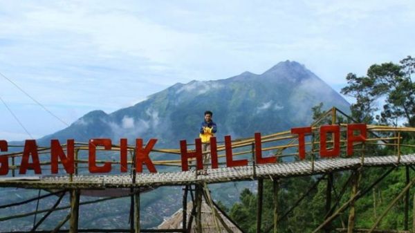 Wisatawan berfoto di atas jembatan bambu berlatarkan Gunung Merbabu, di Wisata Gancik Hill Top, Selo, Boyolali, Jawa Tengah, Sabtu (22/4/2017).