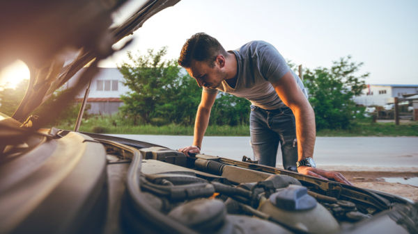 A man looking under his car hood