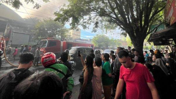 KEBAKARAN: Kebakaran melanda Gedung Aula Idaman yang berada di Jalan Ahmad Yani, Kecamatan Sario, Kota Manado, Jumat (4/7/2025). Warga menyaksikan kebakaran tersebut.