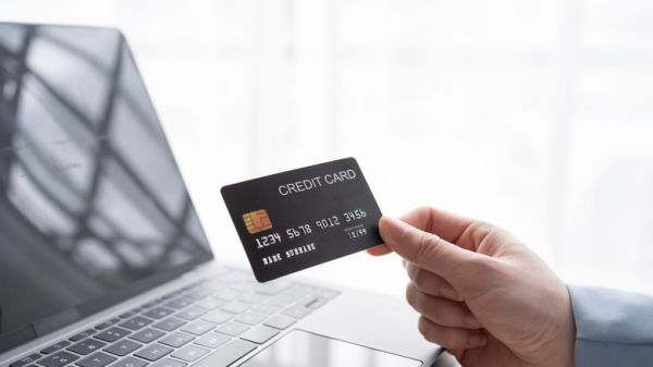 person holding a credit card near a laptop