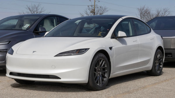 A white Tesla Model 3 parked at a dealership lot.