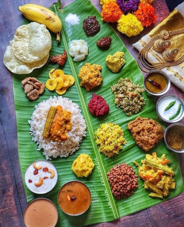 This may contain: a large banana leaf covered in different types of food on top of a wooden table