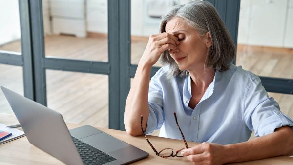 Woman with chronic headaches holding her head at work.