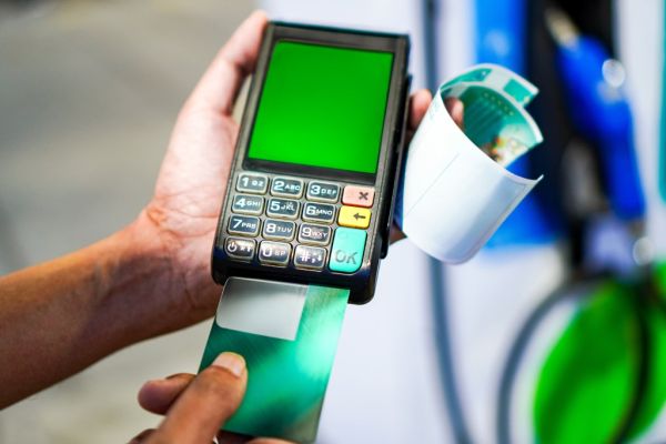 Gas station employee swiping a credit card using a mobile EDC machine.