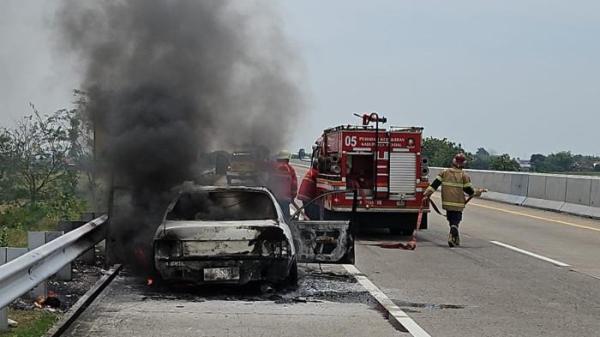 TERBAKAR - Petugas memadamkan mobil Toyota Corolla yang terbakar di jalan tol KM 397-700, Desa Sumbersari Kecamatan Ngampel Kabupaten Kendal. Tidak ada korban jiwa dalam kejadian tersebut. 