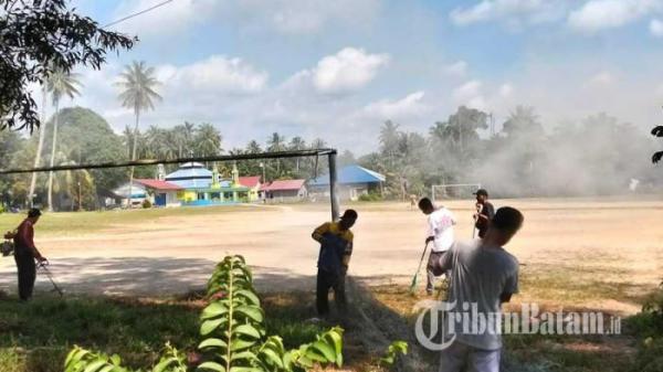 Panitia melakukan gotong royong membersihkan lapangan