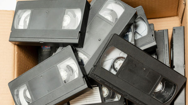 An open cardboard box full of VHS tapes.