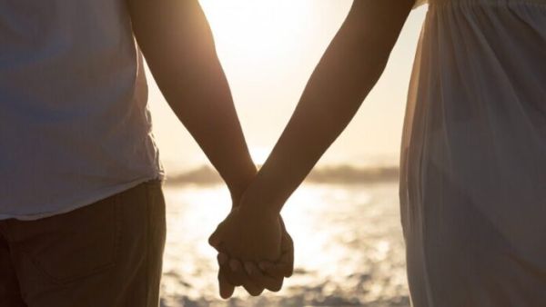 Couple standing together hand in hand on the beach
