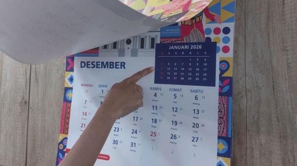 CUTI BERSAMA 2026 - Ilustrasi pegawai menunjukkan kalender 2026. Untuk tahun 2026, total hari libur nasional ditetapkan sebanyak 17 hari sesuai peraturan perundangan yang berlaku. Sementara itu, cuti bersama disepakati sebanyak 8 hari, Senin (1/12/2025).