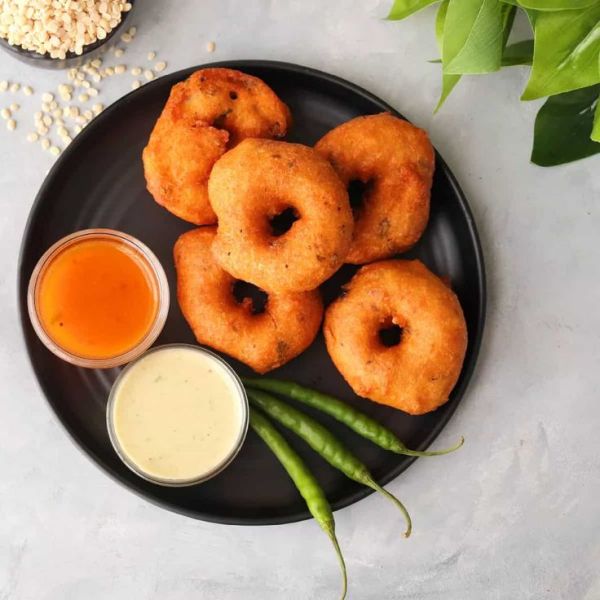 This may contain: some fried food on a black plate with dipping sauces and green beans next to it
