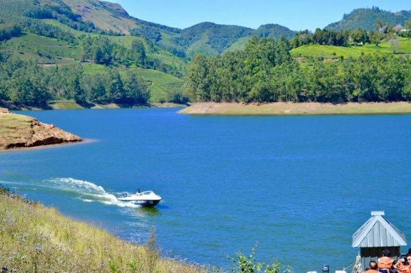 This may contain: a boat traveling down a river next to a lush green hillside
