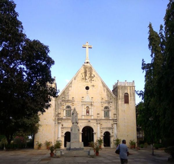 This may contain: a man walking towards an old church with a cross on top