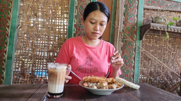 KULINER - Seorang pengunjung tengah menikmati makanan nasi jangan deso di Arumpala Kopi yang berada di Arumpala Kopi, Kecamatan Ngasem Kabupaten Kediri Jawa Timur, Senin (29/12/2025).