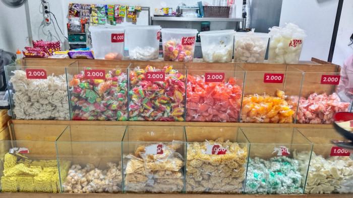 KULINER BOGOR - Berbagai macam jenis kerupuk, mulai dari kerupuk aci putih, kerupuk warna-warni, hingga mie kering, tersaji dalam wadah kaca transparan dengan label harga mulai dari Rp1.000