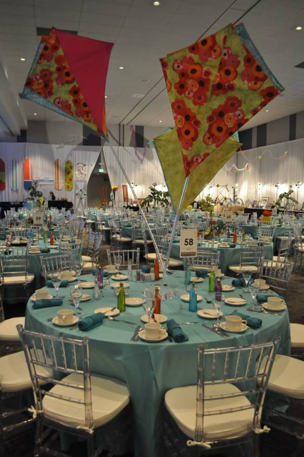 This may contain: an indoor event with tables and chairs set up for a banquet or party, decorated with colorful umbrellas