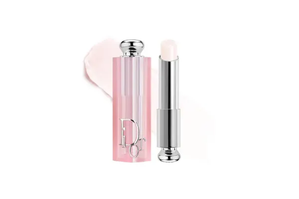 Dior Addict Lip Glow balm in a pink case with a swatch of the product in the background.