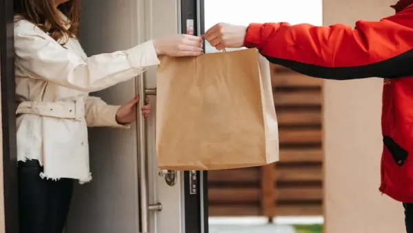 Delivery man giving a bag to woman at her doorstep