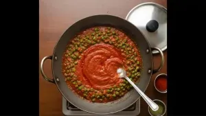 Tomato puree and water are added, salt is mixed in, and the curry is cooked until vegetables are soft and oil separates.