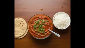 The curry is garnished with fresh coriander leaves and served hot with rice or roti.