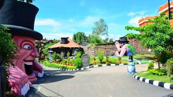 This may contain: the entrance to an amusement park is decorated with fake people and plants, including two large figures