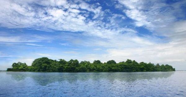 This may contain: an island in the middle of a lake surrounded by trees and blue sky with clouds