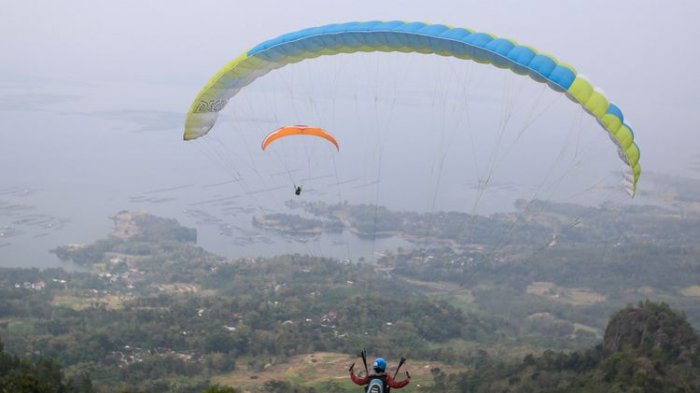 Anggota komunitas Paralayang Solo Raya terbang dari Puncak Joglo, Desa Sendang, Kecamatan Wonogiri, Jawa Tengah, Minggu (10/6/2018). Wisatawan bisa menikmati panorama keindahan alam seperti Waduk Gajah Mungkur dari udara dengan cara terbang tandem bersama instruktur paralayang bersertifikat.