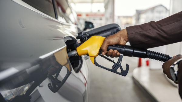 A driver fueling their car with a yellow gas pump