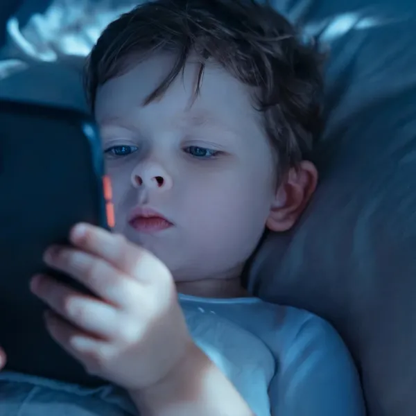 little boy using tablet in bed