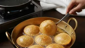 Frying kachoris in hot oil until golden and puffed.