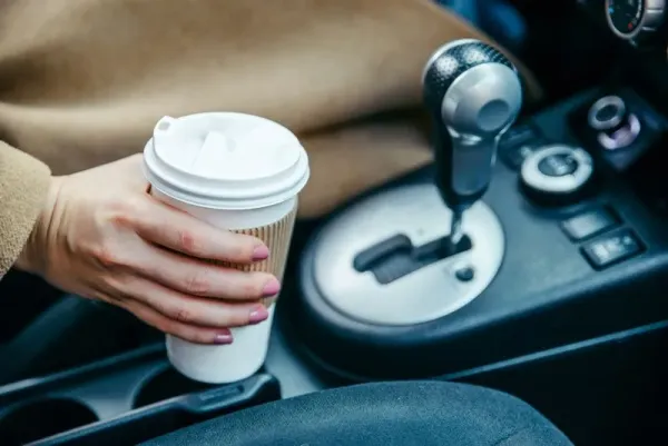 minum kopi woman hand taking cup with coffee in car. close up. crop. morning energy. lifestyle